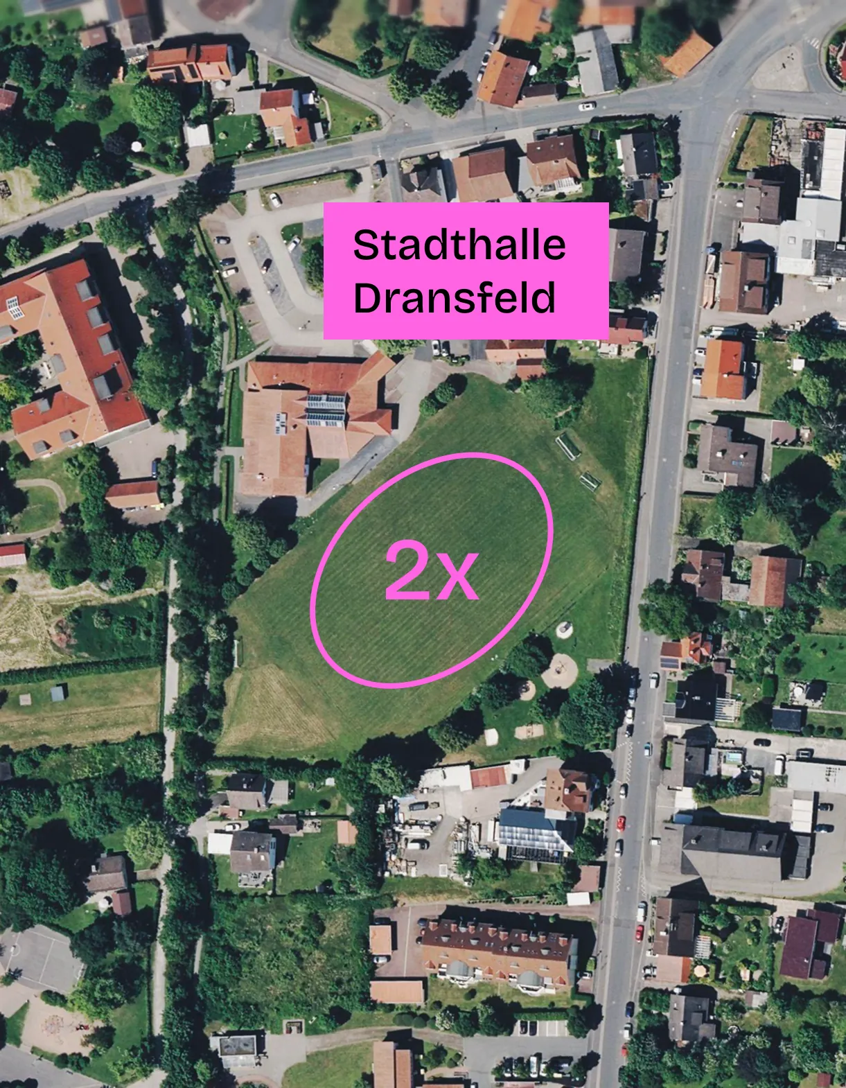 Satellitenbild des Sportplatzgeländes in Dransfeld mit einer pink eingezeichneten Runde auf dem Rasen, beschriftet mit „2x“. Ein pinkes Schild weist die Stadthalle Dransfeld aus.